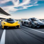 A hypercar and a supercar racing side by side on a sleek, futuristic track, with the hypercar showcasing superior speed and power